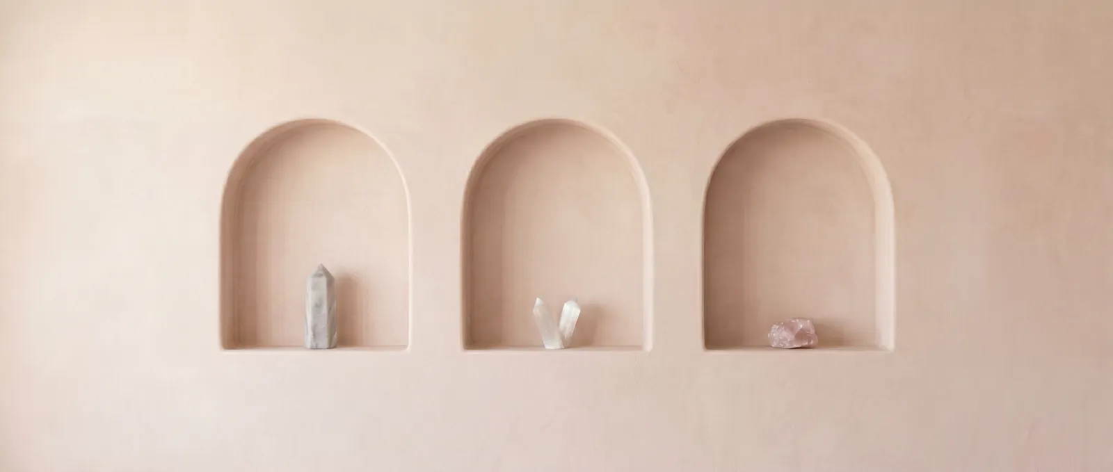 Three arched plaster niches, each holding a single crystal, in the clinic